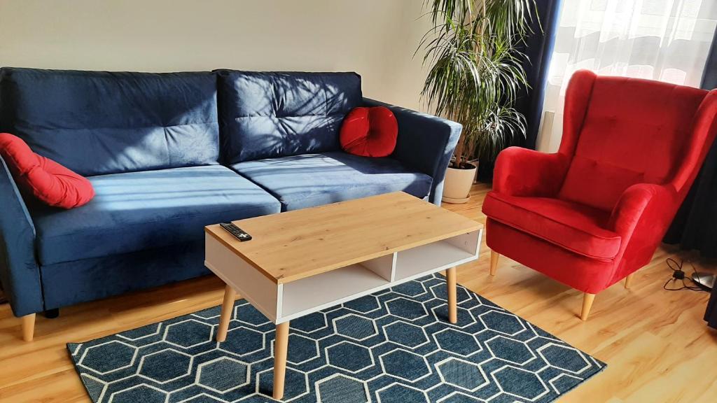 a living room with a blue couch and two red chairs at 9 APARTAMENT VILLA NORD - parking in Jastrzębia Góra