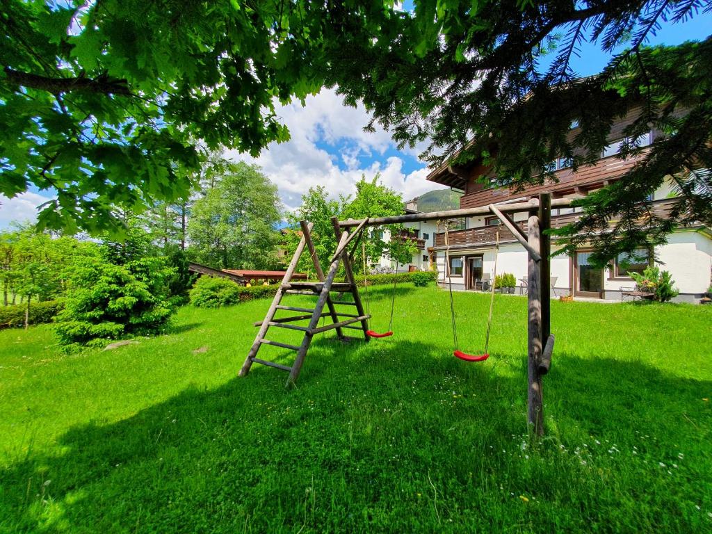 a tree with a swing in a yard at Profelt`s Apartments Uttendorf - Steinbock Lodges in Uttendorf