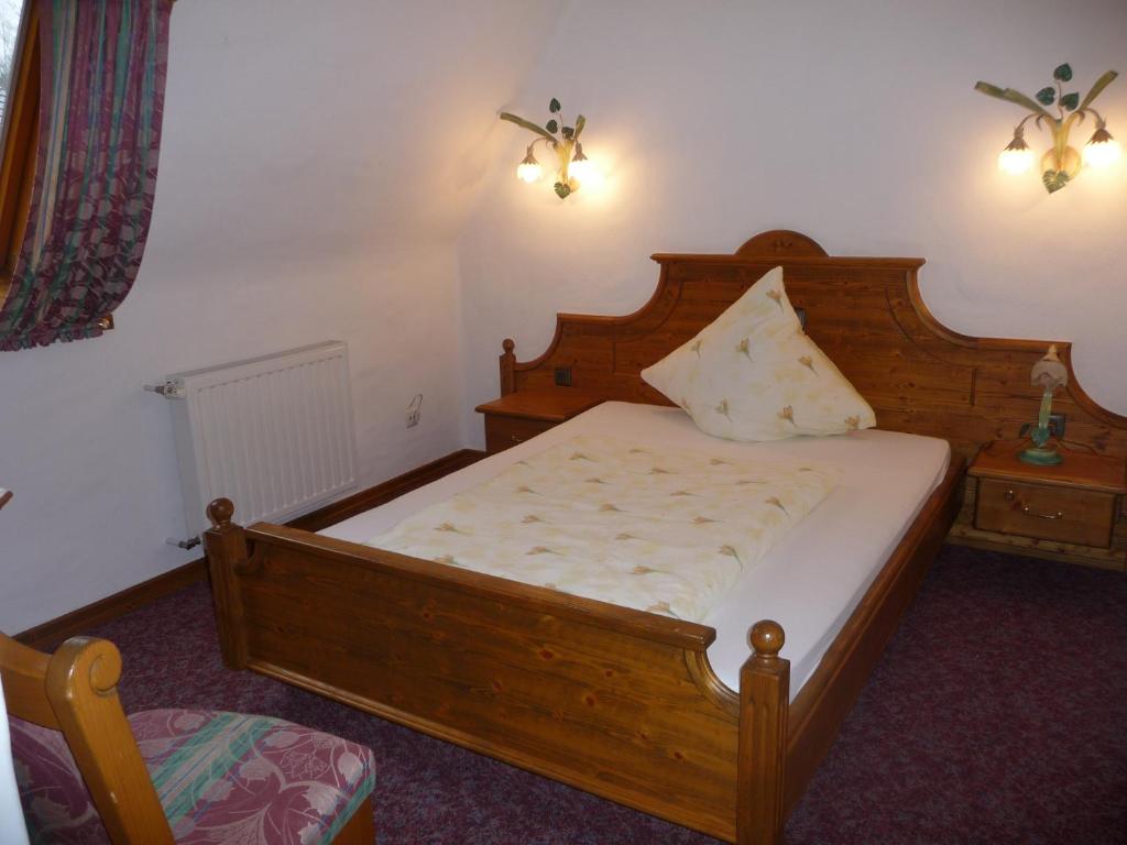 a bedroom with a wooden bed and a night stand at Hotel Haus Tiefenbach in Bullange