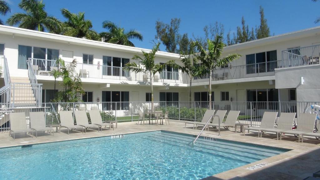 a hotel with a swimming pool and chairs and a building at Tranquilo in Fort Lauderdale