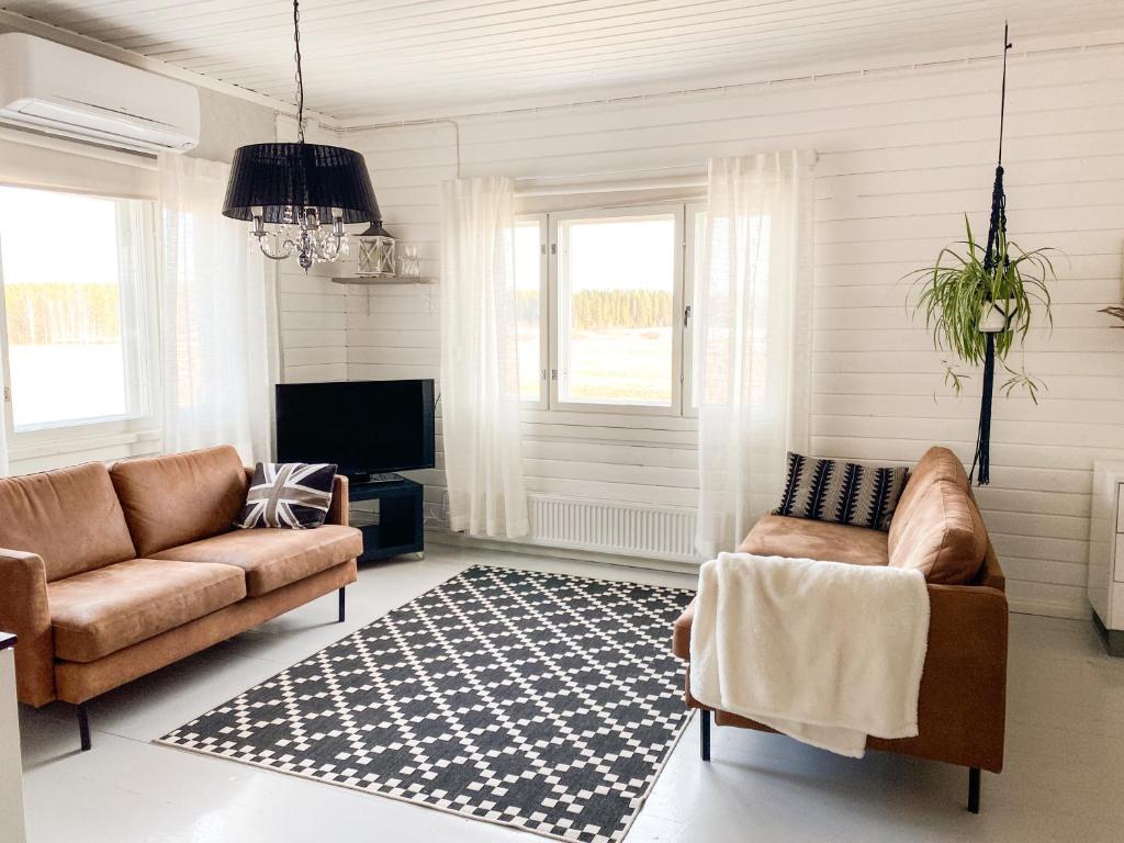 una sala de estar con 2 sofás y una alfombra en Maalaistalo maatilamiljöössä, en Haapavesi