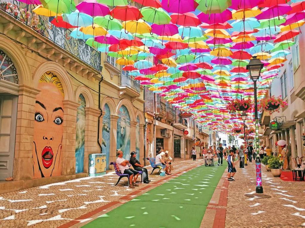 a street with colorful umbrellas hanging from a building at Isatour - Ninho D' Águia in Águeda
