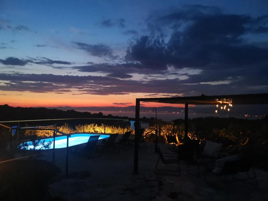 um pôr-do-sol sobre uma piscina num resort em Robinson crusoe style house "MASLINA'' em Škrip