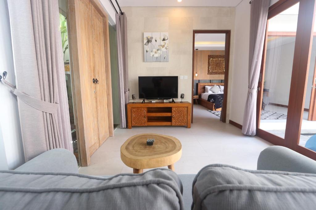 ein Wohnzimmer mit einem TV, einem Sofa und einem Tisch in der Unterkunft Stana Kendran Villa in Ubud