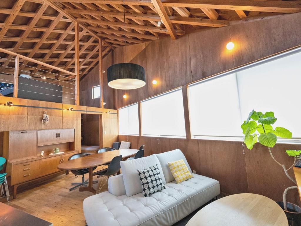 een woonkamer met een witte bank en een tafel bij SUMITSUGU HOUSE Atelier Suite in Kumamoto