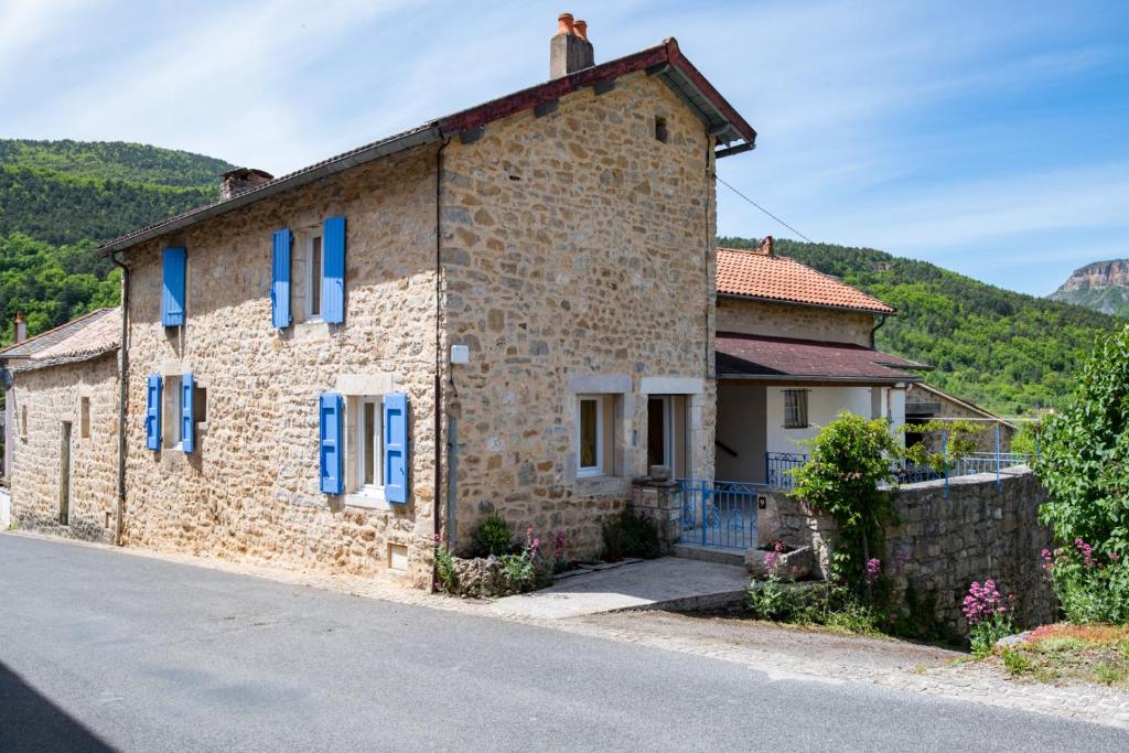 een stenen huis met blauwe luiken op een straat bij Gite les Cerisiers dans les Gorges du Tarn in La Cresse