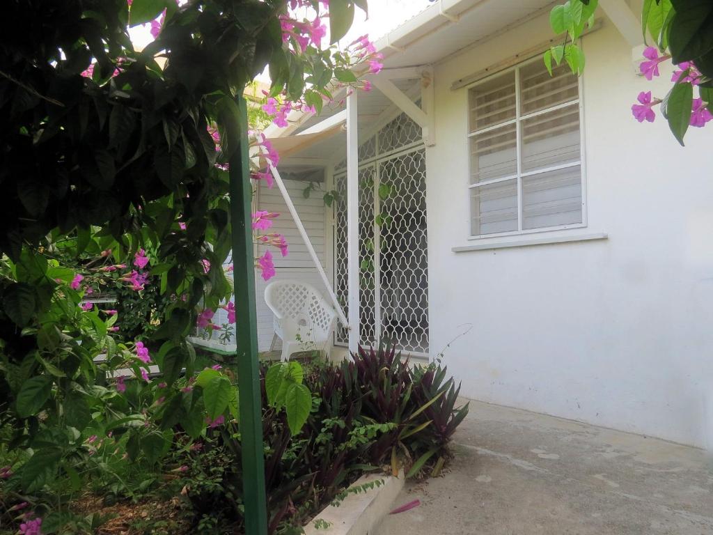 una veranda bianca con una sedia bianca e fiori di Bungalow Soleil a Sainte-Anne