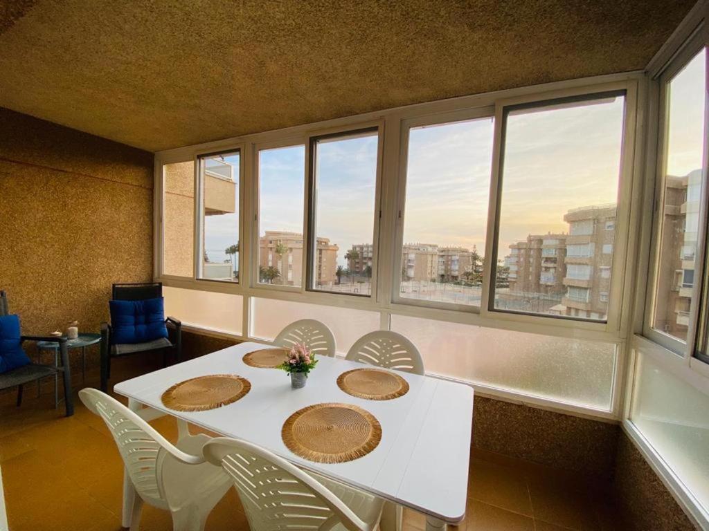 托羅克斯科斯塔的住宿－Apartamento Arena y Sal，一间设有白色桌子、椅子和窗户的用餐室