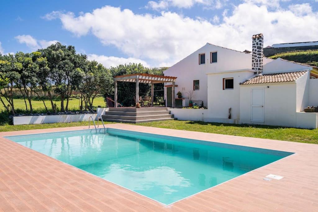 a villa with a swimming pool in front of a house at Country House in Azores - S. Miguel in Ribeira Grande