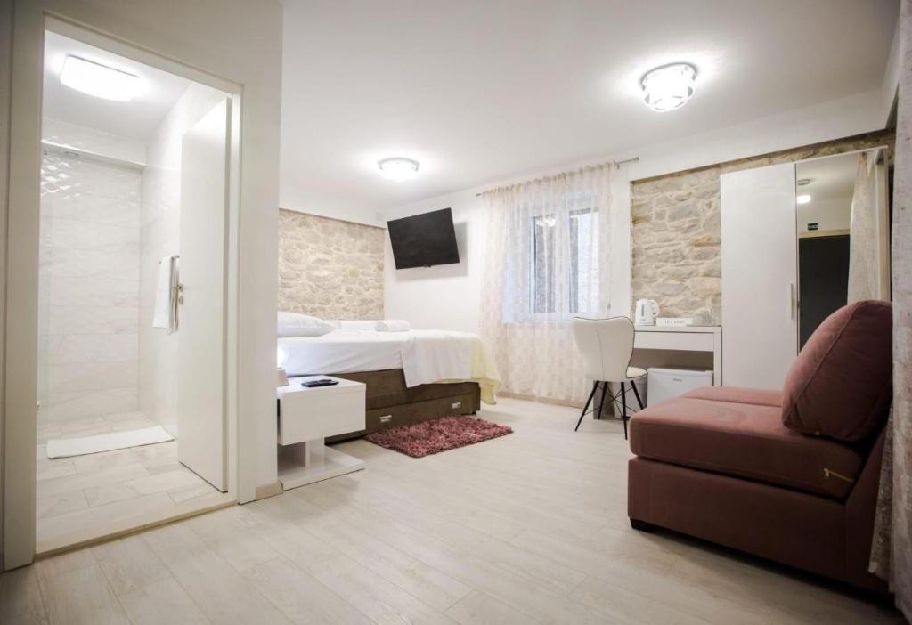 een slaapkamer met een bed en een bank en een badkamer bij Lions luxury rooms in Split