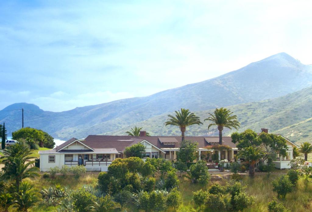 una casa con palmeras y montañas en el fondo en Banning House of Two Harbors, en Two Harbors