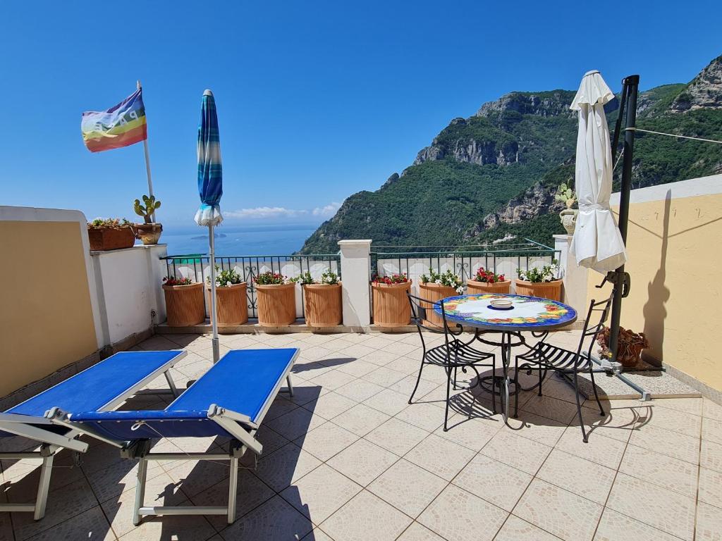 een patio met een tafel en stoelen en uitzicht op de oceaan bij Casa Monticello in Positano