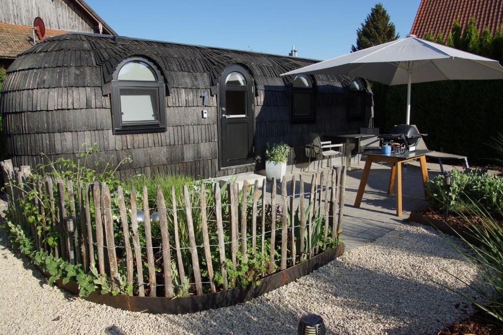 une clôture devant un bâtiment avec un parapluie dans l'établissement Freches Wohnen Igluhuts, à Lindau