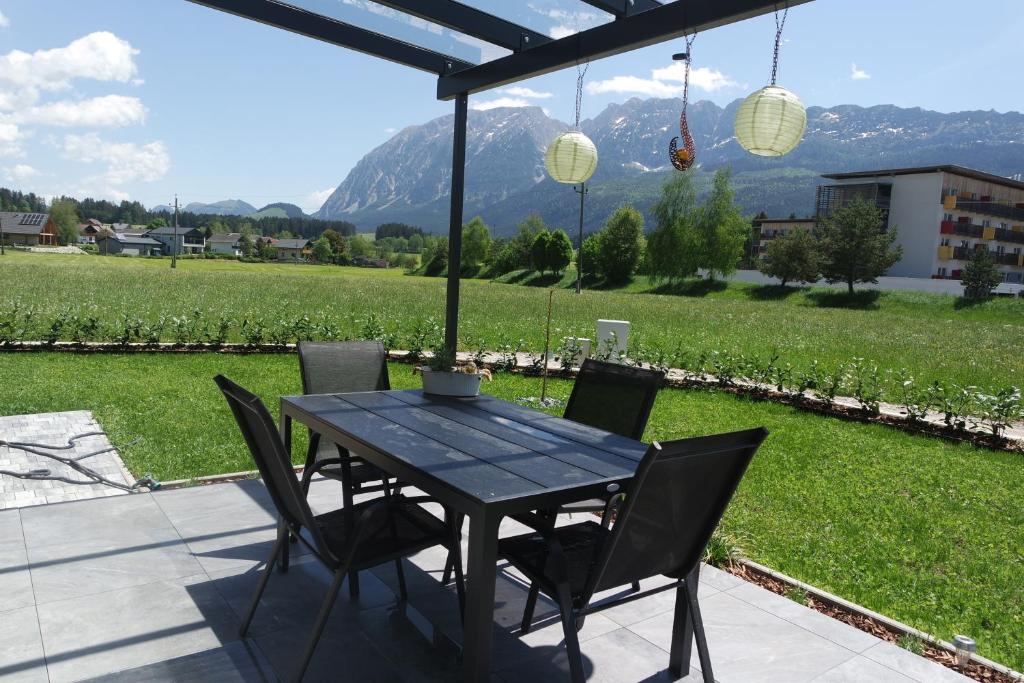 una mesa y sillas en un patio con vistas a un campo en Alpenlodge Bad Mitterndorf en Bad Mitterndorf