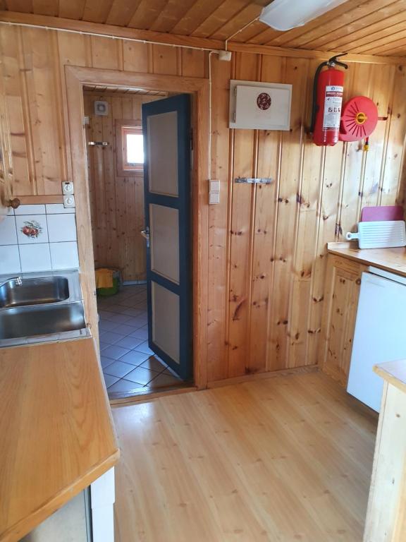 uma cozinha com paredes de madeira e uma porta num quarto em Bjørklund em Geilo
