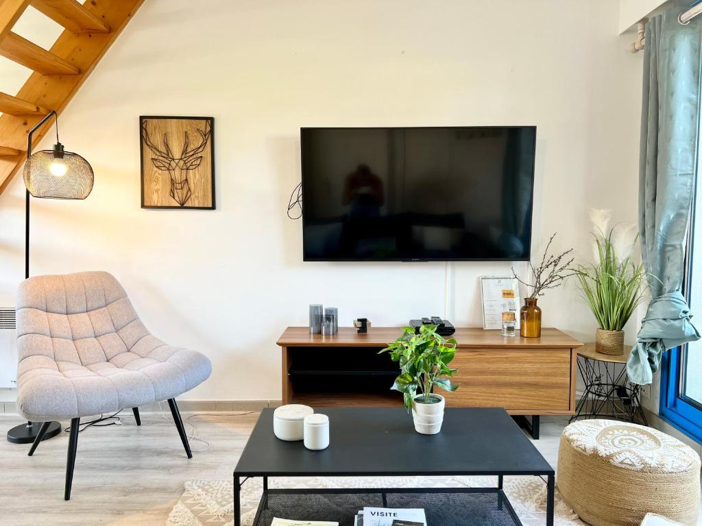 uma sala de estar com uma televisão, uma cadeira e uma mesa em COC - Entre Terre Et Mer em Wissant