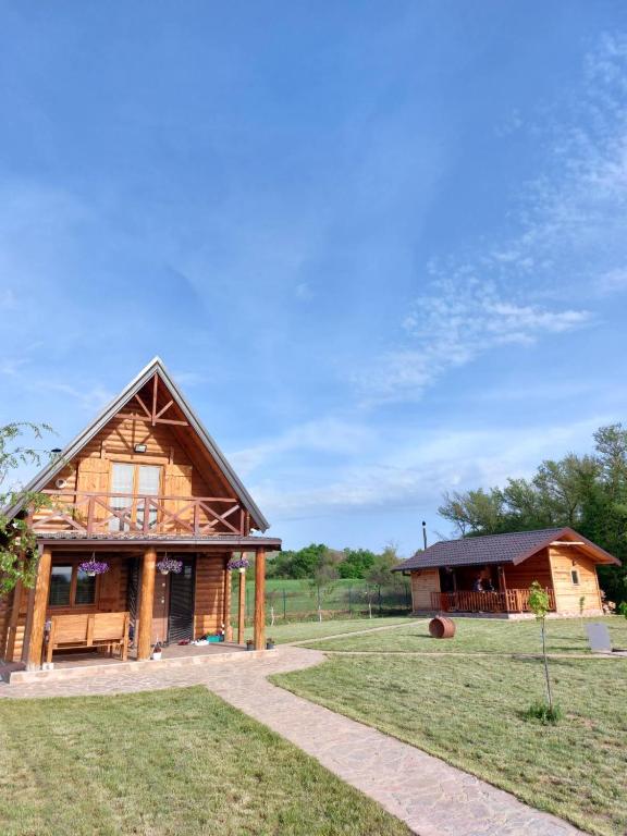 a log cabin with a porch and a building at Log Cabin in Strezovce in Kumanovo