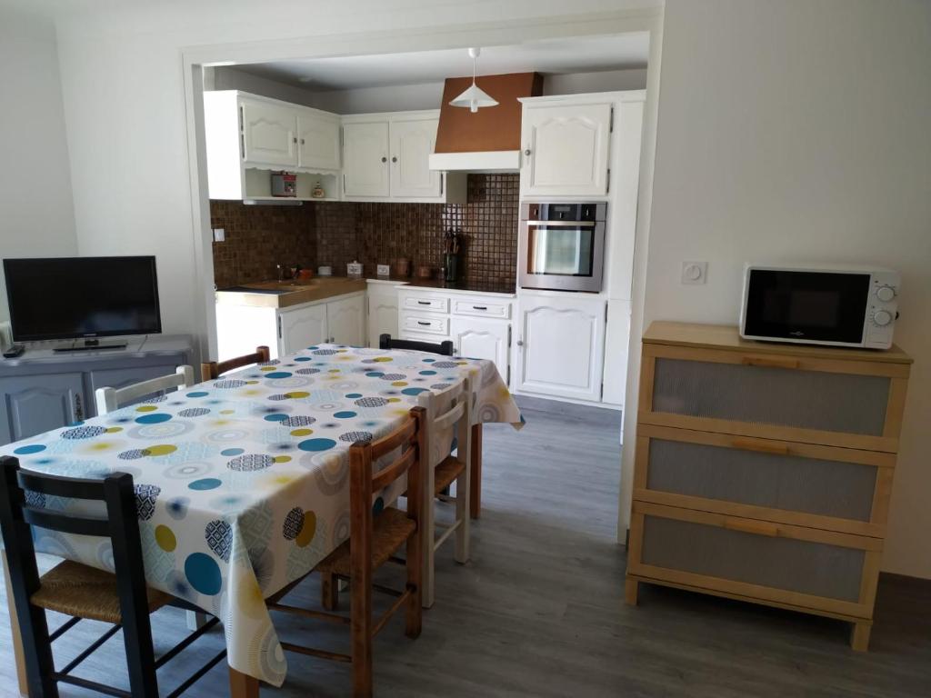 a kitchen with a table with chairs and a kitchen with white cabinets at Gîte familial chaleureux à la campagne 20mn FUTUROSCOPE in Savigny-Lévescault