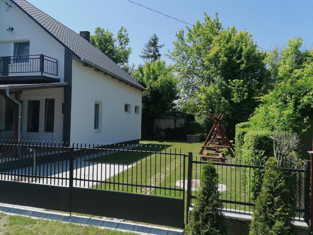 a fence in front of a house with a yard at 7 férőhelyes ház Balatonfenyvesen a tótól 15 m-re saját stéggel és csónakkal in Balatonfenyves