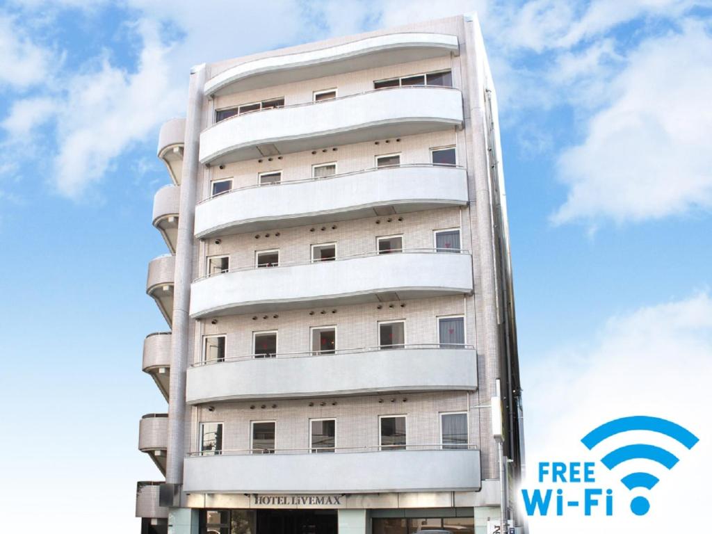 un edificio blanco alto con un letrero de wifi gratuito en HOTEL LiVEMAX BUDGET Tokyo Kiba en Tokio