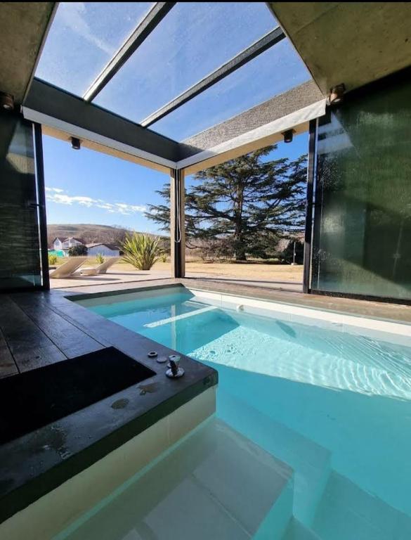 an indoor swimming pool with a large glass window at Casa Cardales MINI PISCINA CLIMATIZADA in Sierra de la Ventana