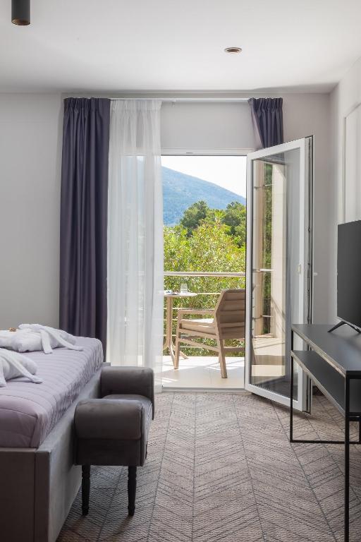 a bedroom with a bed and a desk and a balcony at Zlatni Rat Beach Resort in Bol