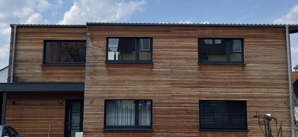 un edificio de madera con ventanas negras. en Haus am See, en Calden