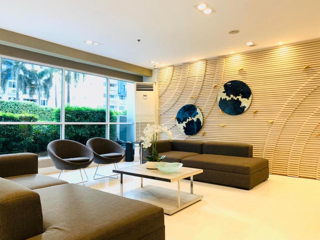 a living room with a couch and two chairs and a table at Sea Residences - Property Val Alano 0995-448-8872 in Manila