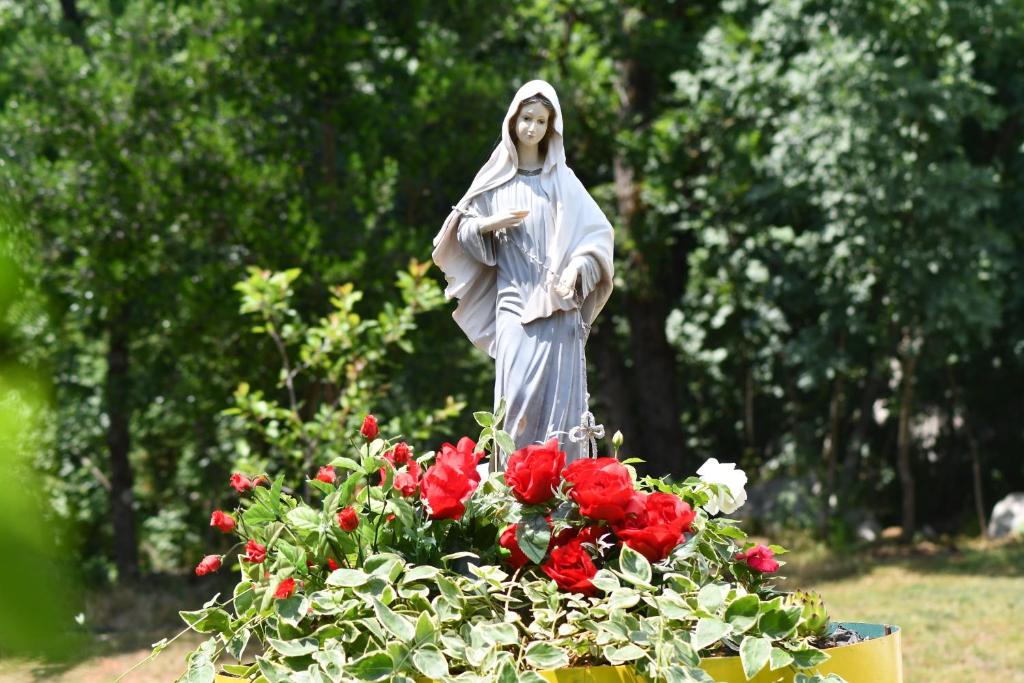 a statue of a nun standing next to flowers at Casa Del Pellegrino M&A - Ostojići in Međugorje