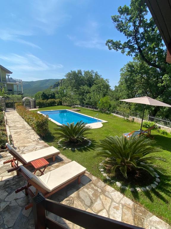 un patio trasero con piscina y sombrilla en El Mar House en Petrovac na Moru