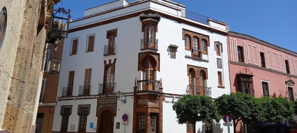 un edificio blanco con una torre de reloj en una calle en Casa Palacio La Casa Blanca Suites, en Sevilla