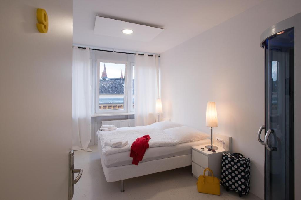 ein weißes Schlafzimmer mit einem Bett und einem Fenster in der Unterkunft Business Hostel Wiesbaden ONE in Wiesbaden