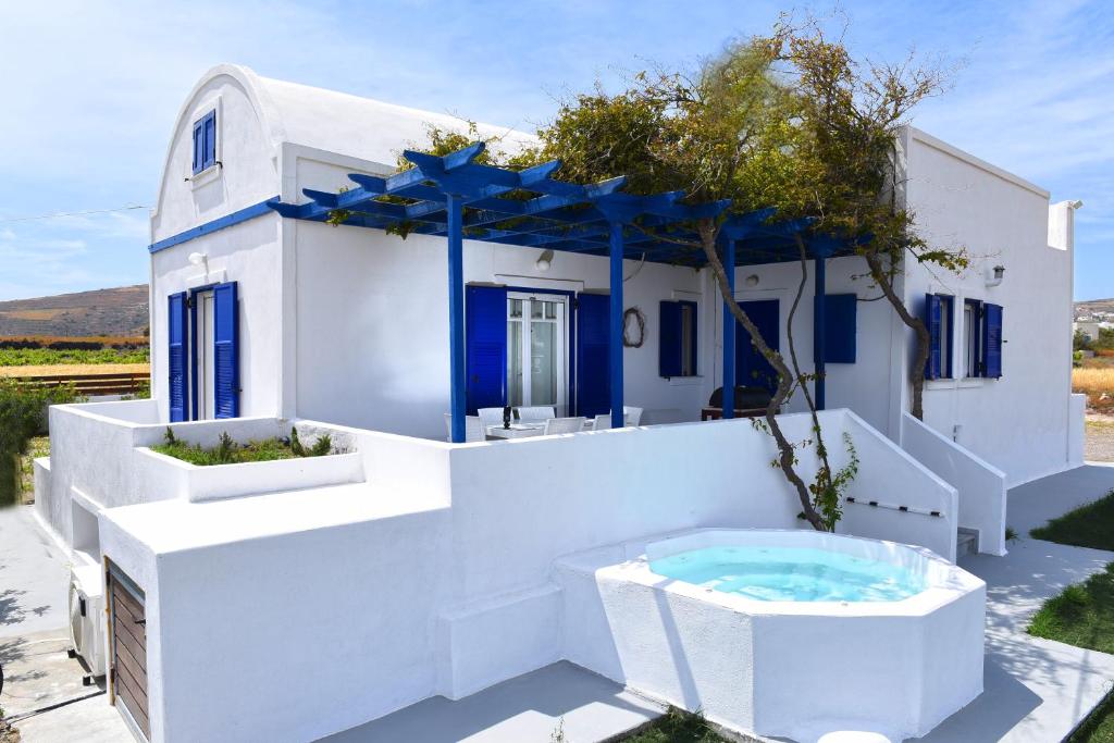 une maison blanche avec un bain à remous en face de celle-ci dans l'établissement Villa Angelica, à Perivolos