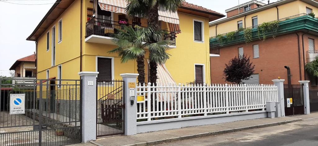 a white fence in front of a yellow house at Appartamento "MARY" in Collegno