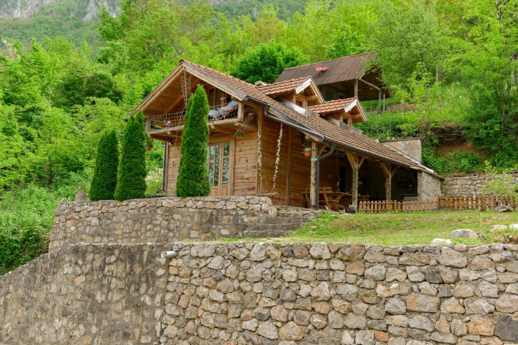 a wooden house behind a stone wall at Drinska Villa Cabin in Perućac