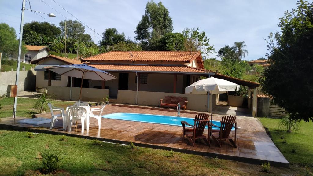 um quintal com piscina e cadeiras e uma casa em Chácara do Juscelino em Monte Sião