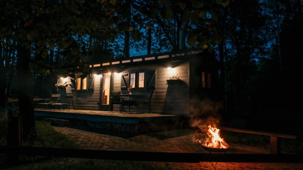 a cabin with a fire in front of it at night at Chata u lesa RANCH NA HRANICI in Baška