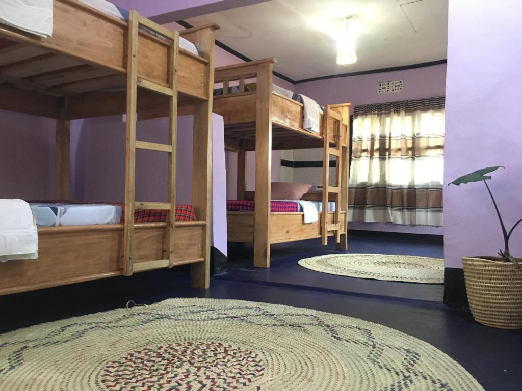a room with two bunk beds and a rug at Ava garden backpackers in Mto wa Mbu