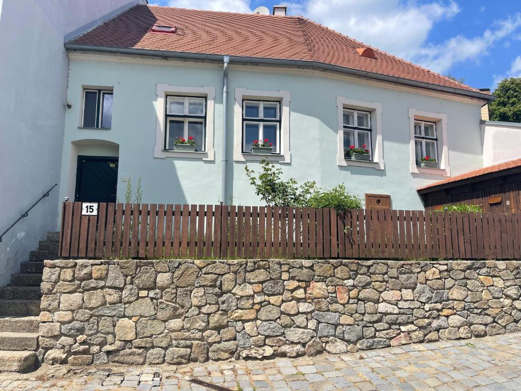 een wit huis met een hek en een stenen muur bij Apartmán RAST in Třebíč