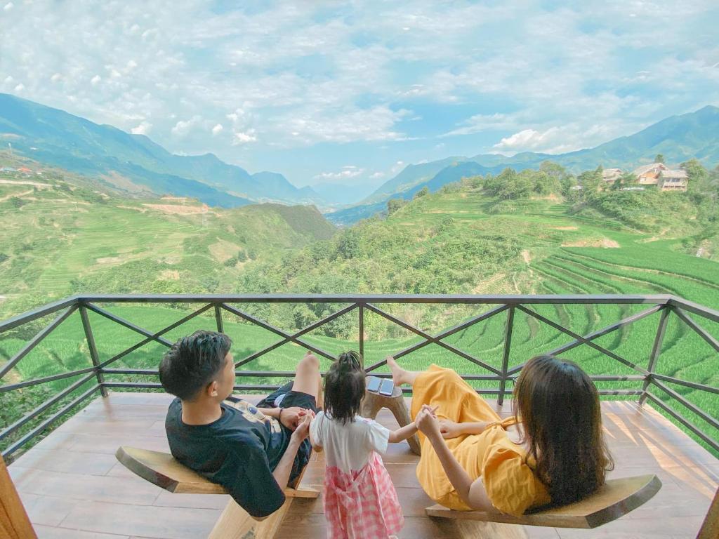 un grupo de personas sentadas en un balcón con vistas a las montañas en Chapa Ecolodge en Sa Pa