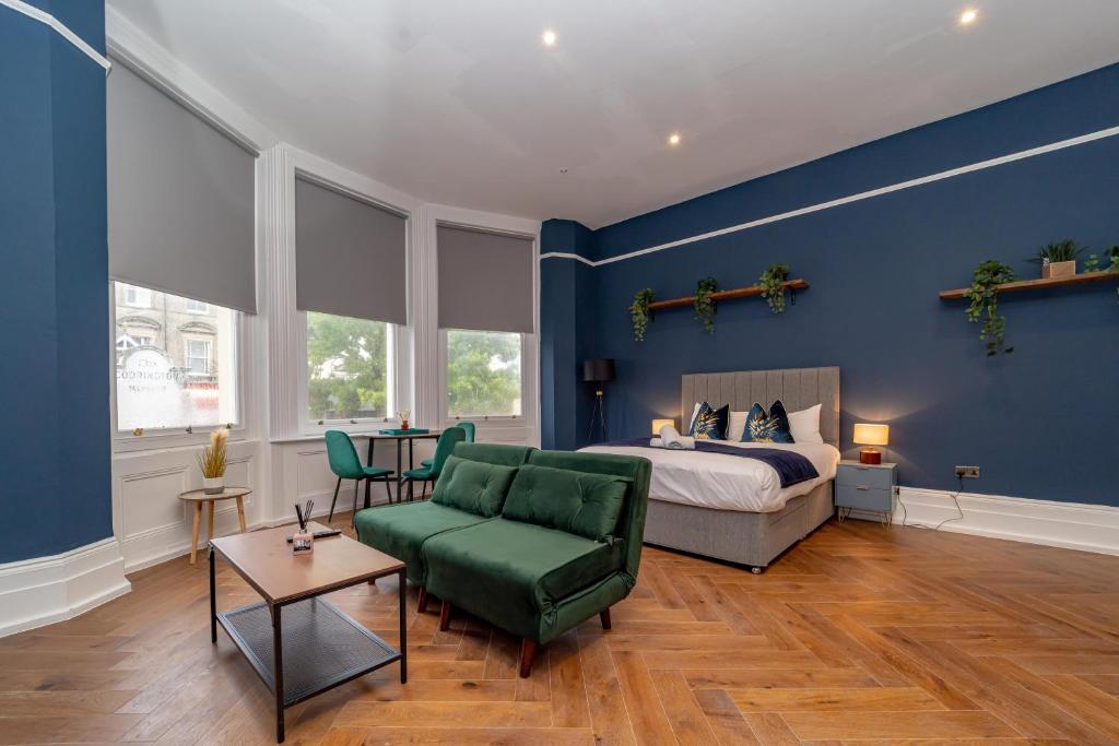 1 dormitorio con paredes azules, 1 cama y 1 silla verde en 1ST MORDEN STUDIO FLAT Moments away from Brighton seafront, en Brighton & Hove