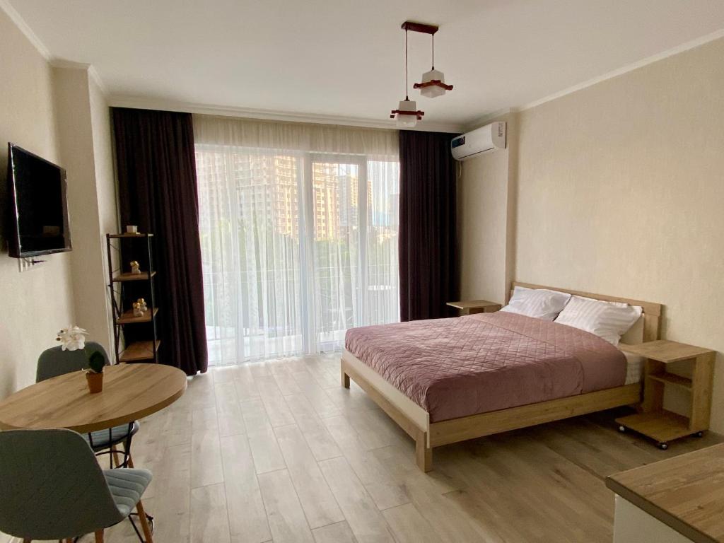 sypialnia z łóżkiem, stołem i oknem w obiekcie Orange Batumi Travel w mieście Batumi