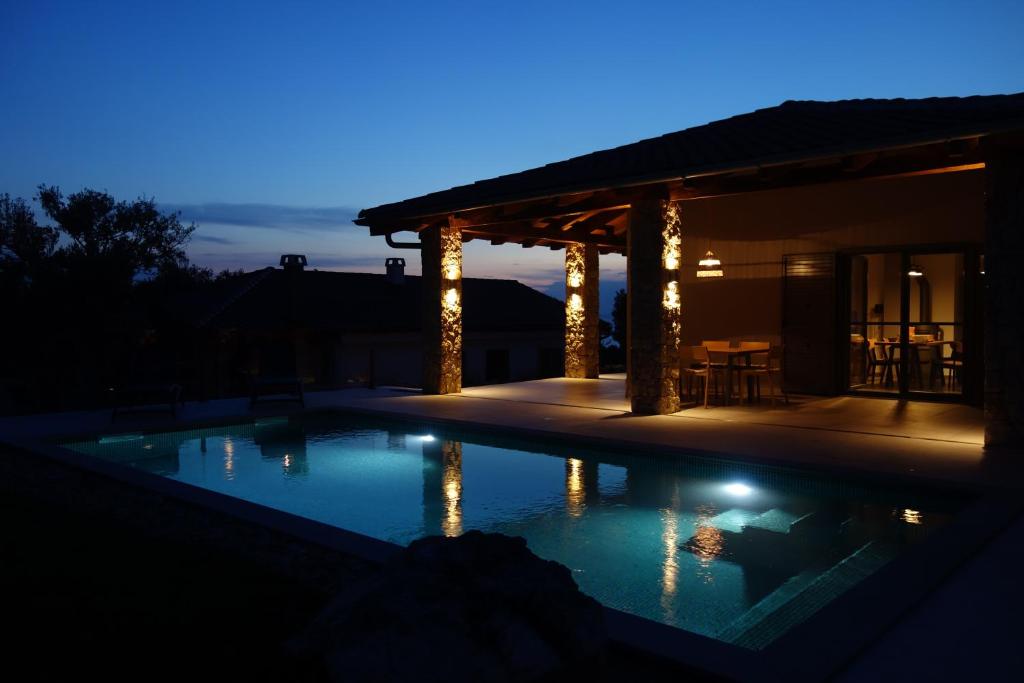 una piscina en un patio trasero por la noche en Villa Kadila with heated pool and sauna for family en Lun