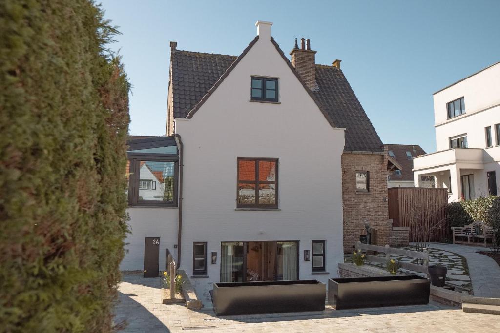 an external view of a white house at Nieuw app met tuin en terras, gratis parking, aan zee, vlakbij Brugge in Duinbergen