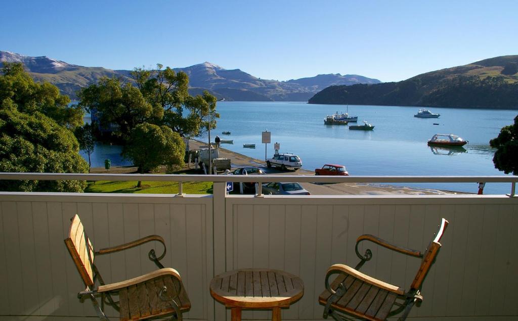 two chairs and a table on a balcony overlooking a body of water at Akaroa Village Inn in Akaroa