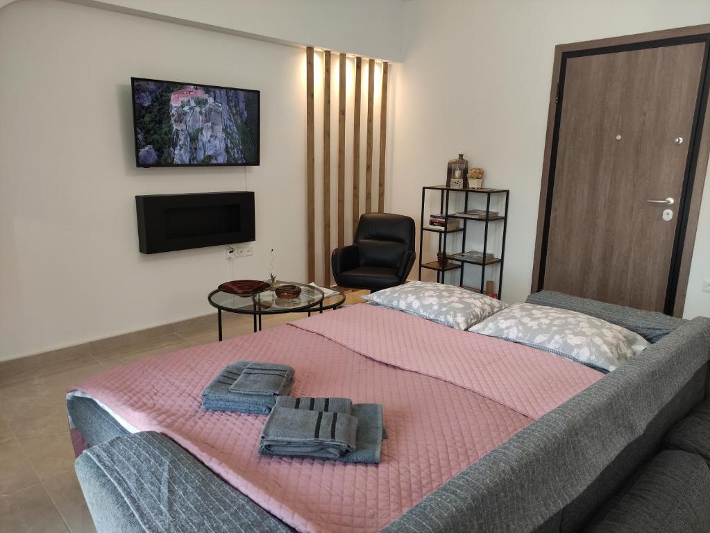una camera con un letto con una coperta rosa e una sedia di Grey Swan - Modern & Stylish apartment with Private Parking a Volos