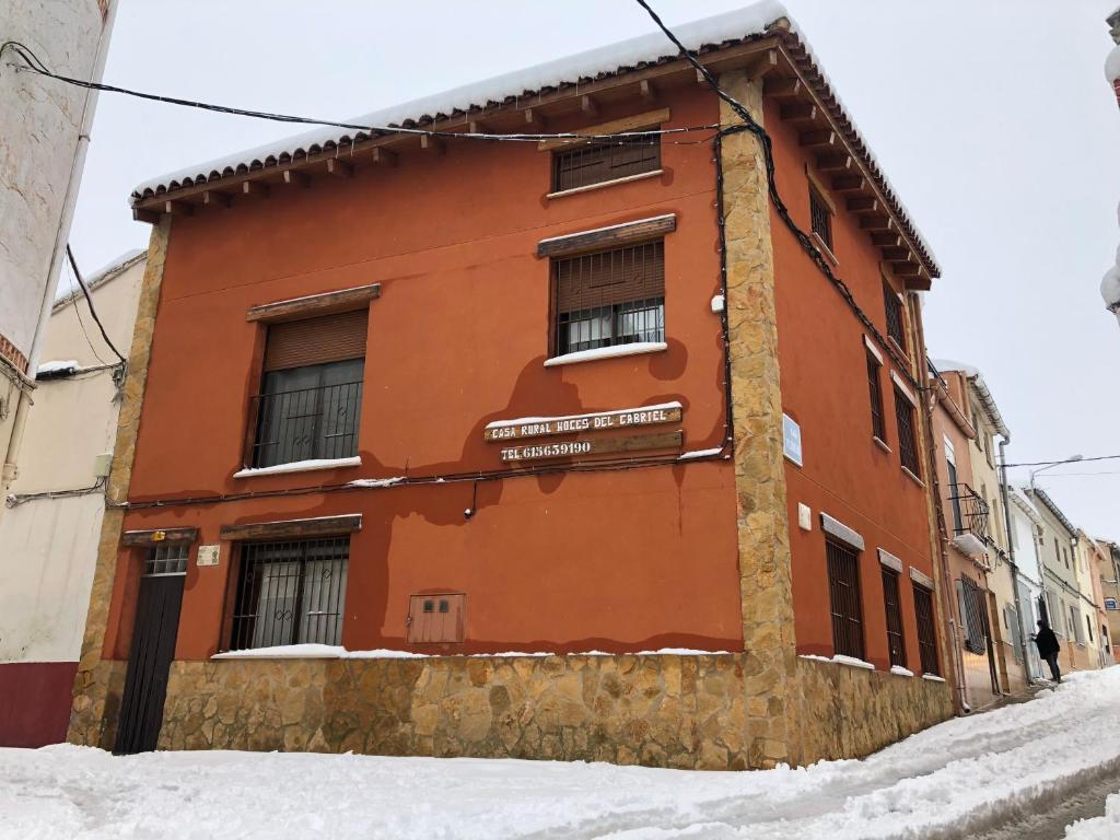 un edificio rojo con nieve delante en Casa Rural Hoces del Cabriel en Villargordo del Cabriel