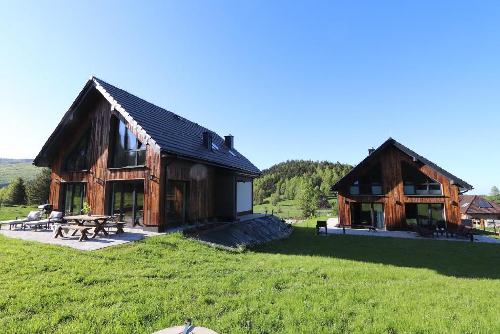 a large wooden house with a picnic table in a field at Domy Pod Babią in Zawoja