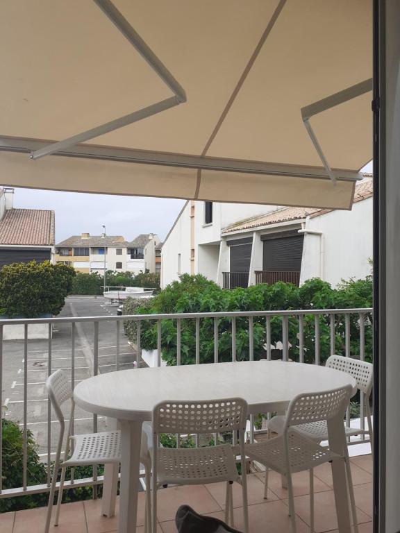 une table blanche et des chaises sur un balcon dans l'établissement Le Frioul, au Grau-du-Roi