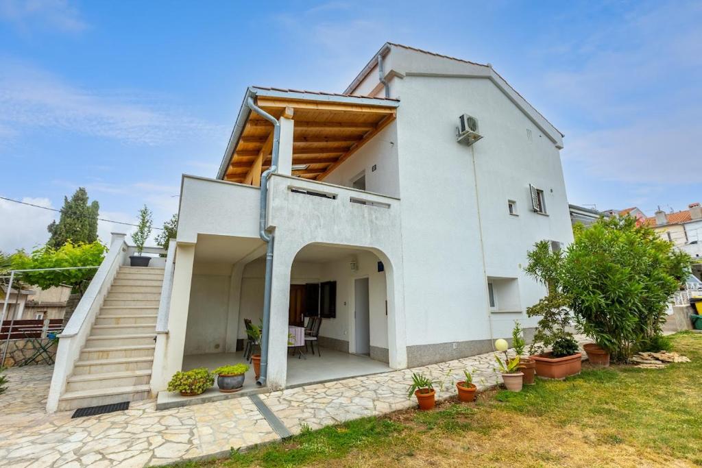 ein weißes Haus mit einer Veranda und einer Treppe in der Unterkunft Apartment Anton in Punat